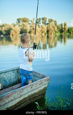 Vue arrière du petit garçon avec la canne à pêche en bateau permanent Banque D'Images