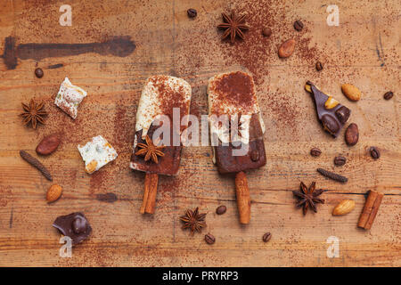 Des espresso et chocolat blanc sucettes glacées avec des épices d'hiver sur fond de bois Banque D'Images