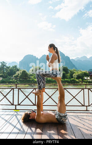 Le Laos, Vang Vieng, jeune couple faisant l'acro-yoga sur une terrasse Banque D'Images