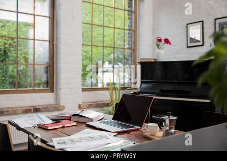 Bureau à domicile avec piano en arrière-plan au loft confortable Banque D'Images