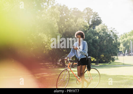 Young woman with cell phone poussant location in park Banque D'Images