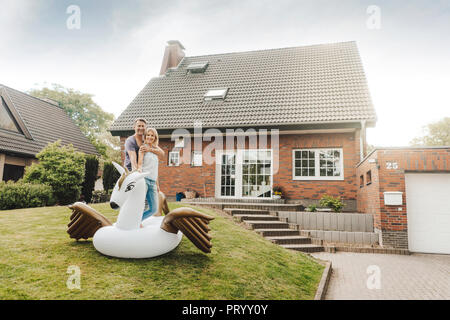 Portrait of smiling mature couple avec piscine gonflable jouet dans jardin de leur maison Banque D'Images