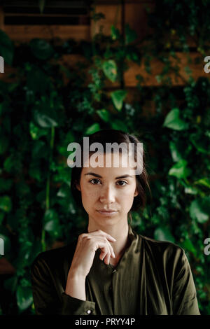 Le portrait de jeune femme au mur avec plantes grimpantes Banque D'Images