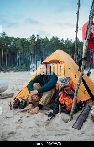 Backpacker assis devant sa tente sur la plage Banque D'Images