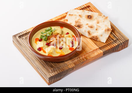 Satsivi à la sauce dinde et aux noix - cuisine géorgienne/arménienne traditionnelle. Servi dans un bol sur une planche de bois avec des tranches de pain plat. Banque D'Images