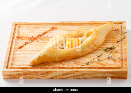 Khachapuri traditionnel arménien sur une planche en bois (pain au fromage farci à l'oeuf et le beurre) sur fond blanc Banque D'Images