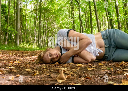 Portrait d'une femme blonde couchée sur le sol dans les bois Banque D'Images