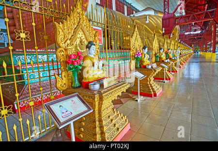 YANGON, MYANMAR - février 27, 2018 : Les petites statues de Bouddha sculptées sur les trônes d'or le long de l'image géante de Bouddha Couché Chaukhtatgyi Modèle caractéristique Banque D'Images