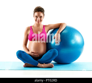 Smiling pregnant woman sitting with fit ball isolé sur fond blanc. Concept de vie sain Banque D'Images