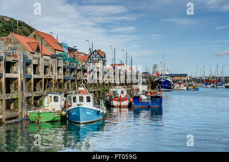 Un cadre tranquille photo de bateaux de pêche colorés amarrés dans le port de Scarborough contre le quai en bois sur une structure calme belle journée d'été. Banque D'Images