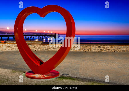 Adelaide, Australie - Novembre 11, 2016 : la plage de Glenelg jetty pans sur Jayd Van Der Meer's grand cœur au coucher du soleil d'installation Banque D'Images