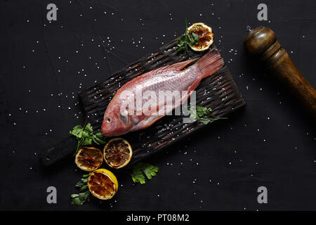 Fruits de mer frais et délicieux poisson rouge rougets sur table sombre, vue du dessus. La vie encore. Mise à plat Banque D'Images