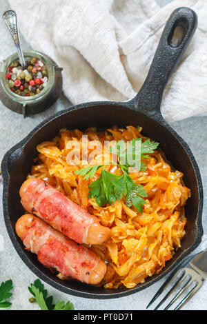 Compotée de chou avec carottes, oignons et tomates et saucisses au bacon avec le persil et les épices dans une poêle en fonte. Le Bigos. Délicieux déjeuner. F sélective Banque D'Images