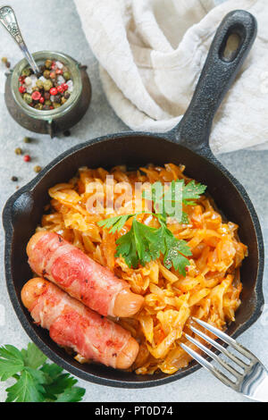 Compotée de chou avec carottes, oignons et tomates et saucisses au bacon avec le persil et les épices dans une poêle en fonte. Le Bigos. Délicieux déjeuner. F sélective Banque D'Images