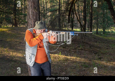 Objectif chasseur Senior fusil en forêt s'appuyant sur un pin Banque D'Images