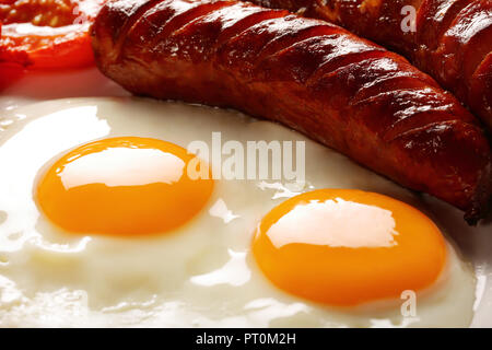 Petit déjeuner anglais avec des saucisses, des tomates grillées, des œufs, du bacon, des haricots et du pain on white plate Banque D'Images