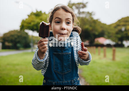 Portrait de l'adorable petite fille profiter de la consommation de crème glacée. Cute young girl eating chocolate candy icecream. Banque D'Images