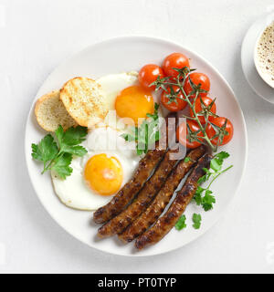 Les œufs, saucisses et tomates cerises sur plaque sur fond noir en blanc. Vue de dessus, Close up Banque D'Images