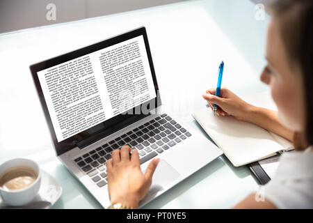 Close-up of a Businesswoman Reading Informations sur l'ordinateur portable sur le lieu de travail Banque D'Images