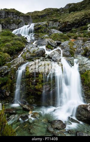 Une cascade cascades en bas d'une colline rocheuse, vert sur l'île du sud de la Nouvelle-Zélande, le long de la Routeburn Track. Banque D'Images
