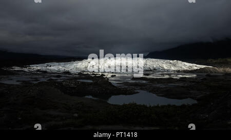 Une étroite bande de lumière du soleil par des nuages épais sur un jour sombre pour illuminer la face de la Matanuska Glacier en Alaska Banque D'Images