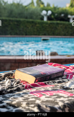 Livre sur une serviette, transats au bord de la piscine, le meilleur concept de vie, de détente, de relaxation, de refroidissement, de l'été, temps de détente extérieure livre, unplugged Banque D'Images