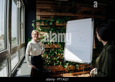 Two businesswomen working de paperboard dans bureau vert Banque D'Images