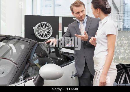 Au concessionnaire, Salesman talking to client à voiture décapotable Banque D'Images