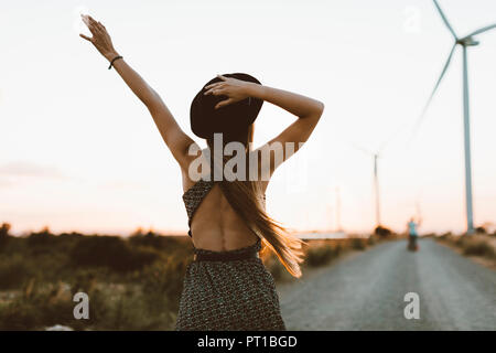 Vue arrière de jeune femme au coucher du soleil on rural road Banque D'Images