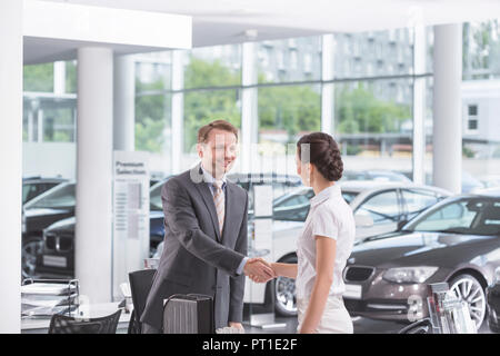 Au concessionnaire, Vendeur et client shaking hands Banque D'Images