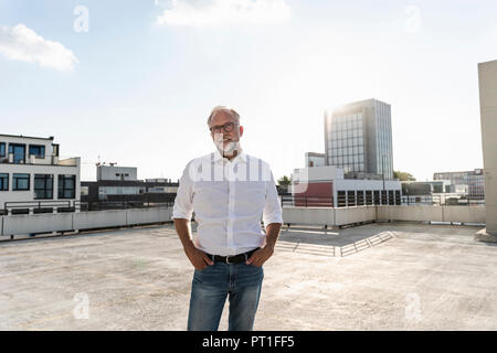 Couple sur le toit d'un immeuble de grande hauteur, avec les mains dans les poches Banque D'Images