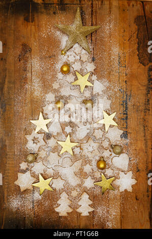 Les biscuits de Noël et des boules de Noël d'or et étoiles formant sur le bois de l'arbre de Noël Banque D'Images