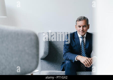 Portrait of mature businessman sitting on couch dans son bureau Banque D'Images