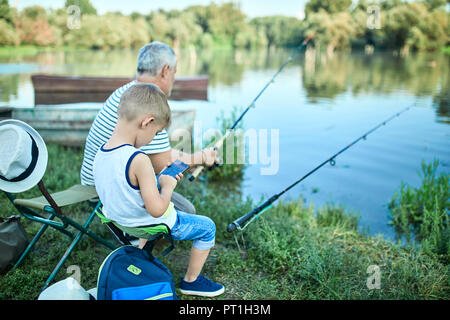 Petit garçon assis avec son grand-père au lakeshore smartphone test Banque D'Images