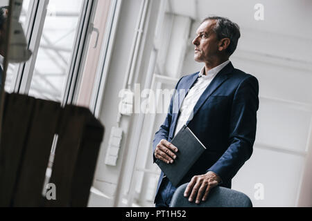 Mature businessman looking out of window Banque D'Images