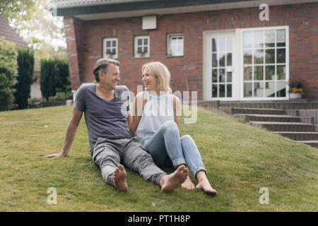Couple assis dans le jardin de leur maison Banque D'Images