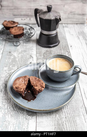 Muffin au chocolat avec du chocolat liquide sur la plaque avec une tasse à café Banque D'Images