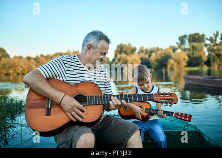 Grand-père teaching grandson playing guitar Banque D'Images