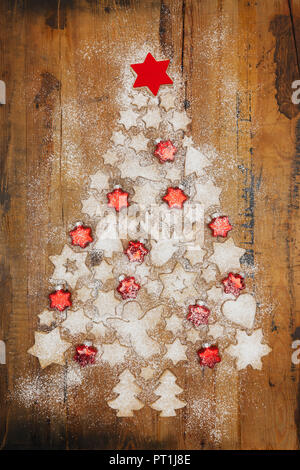 Les biscuits de Noël et red star-shaped Christmas baubles formant Arbre de Noël sur fond de bois Banque D'Images