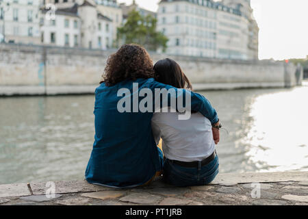 France, Paris, vue arrière du jeune couple assis sur un mur à fleuve Seine Banque D'Images