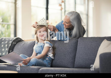 Grand-mère jouant avec sa petite-fille, puuting sur sa tête la couronne Banque D'Images