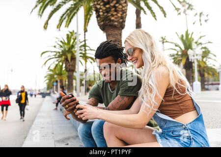 Espagne, Barcelone, multiculturelle, jeune couple assis à côté de la promenade Banque D'Images