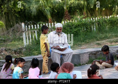 Islamabad, Pakistan. 5Th Oct, 2018. Un enseignant vérifie les devoirs d'un étudiant à une école de fortune mis en place dans un parc public à Islamabad, capitale du Pakistan, le 5 octobre 2018. La Journée mondiale des enseignants est célébrée le 5 octobre. Credit : Ahmad Kamal/Xinhua/Alamy Live News Banque D'Images