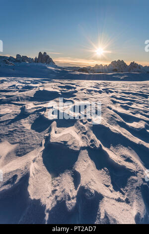 Piazza Prato / Plätzwiese, Dolomites, province de Bolzano, le Tyrol du Sud, Italie, les modèles à vent-neige érodés, dans l'arrière-plan le soleil levant et les célèbres sommets des Tre Cime di Lavaredo Banque D'Images