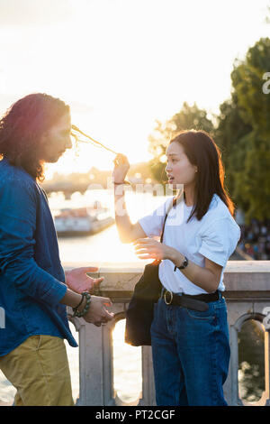 France, Paris, young couple debout sur un pont dans la Seine au coucher du soleil Banque D'Images