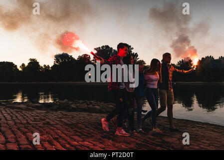 Groupe d'amis de marcher au bord du fleuve dans la soirée aux flambeaux Banque D'Images