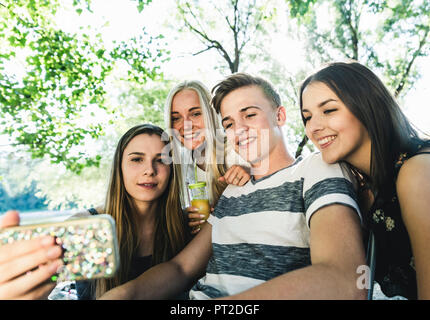 Group of smiling friends looking at cell phone outdoors Banque D'Images