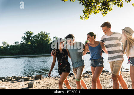 Groupe de professionnels amis marchant bras dessus bras dessous au Riverside Banque D'Images