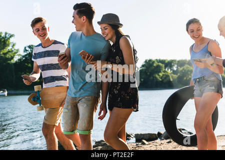 Groupe d'amis heureux avec des téléphones de marcher au bord du fleuve Banque D'Images