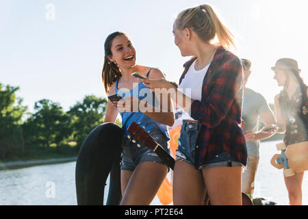 Groupe d'amis heureux avec des téléphones de marcher au bord du fleuve Banque D'Images